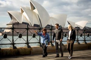 Australian Aborginal tour guide leading a couple across Sydney Harbour
